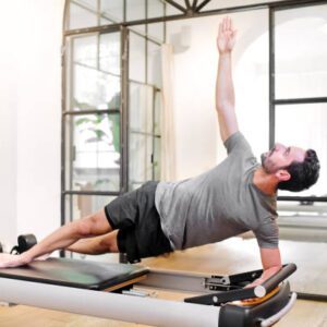A man is doing a pilates exercise on the reformer.